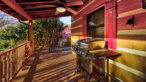 Eine überdachte Veranda mit Grill, Holzwertlauf und Deckenventilator.