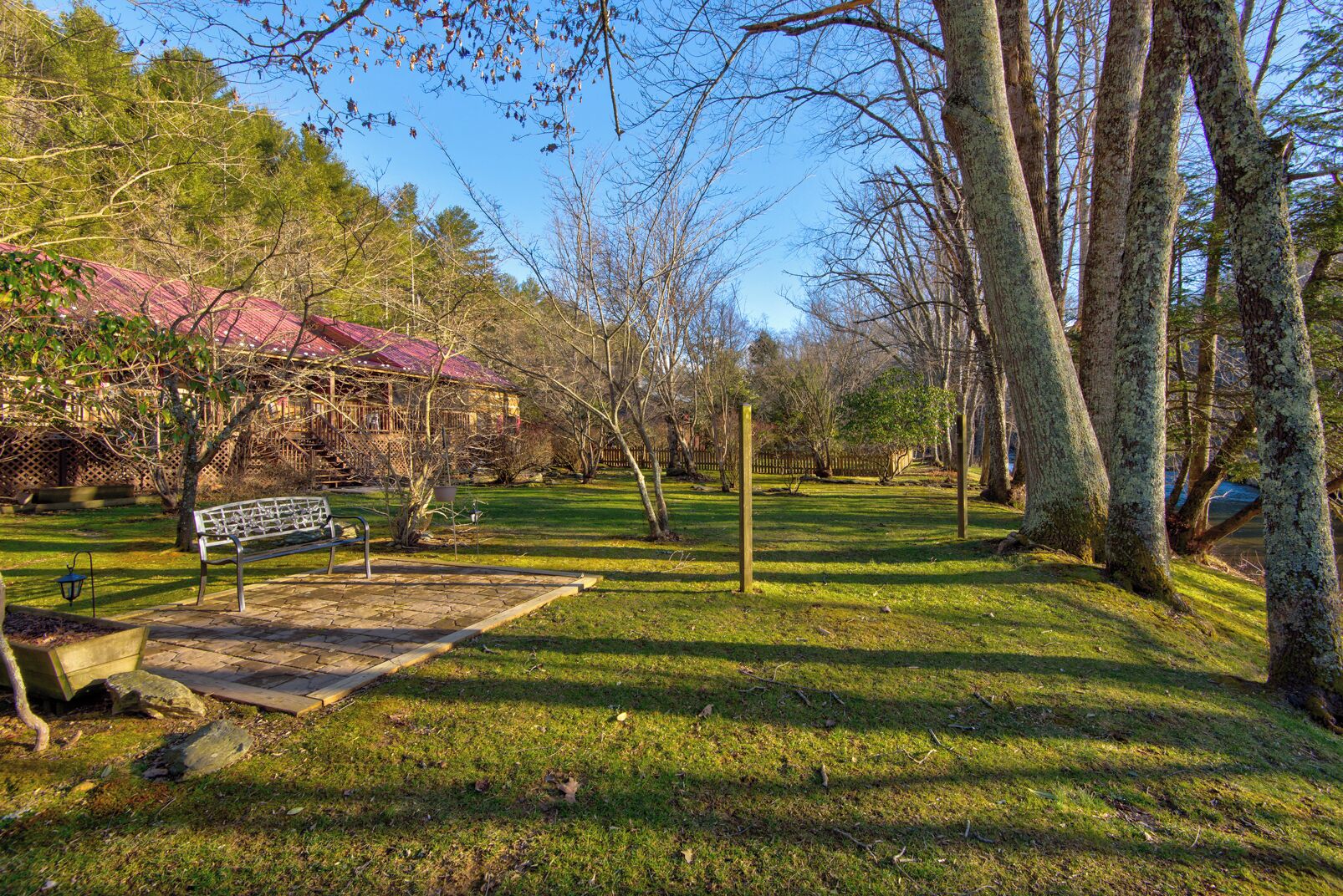 A park with a wooden bench, a picnic table, and a red-roofed building.