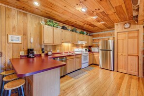 Una cocina con armarios de madera, un refrigerador de acero inoxidable y una encimera de madera.