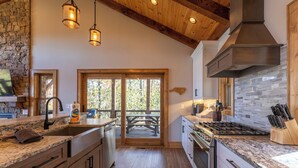 A modern kitchen with granite countertops, stainless steel appliances, and a stone backsplash. - Hidden Gem at Eagles Nest (Banner Elk)