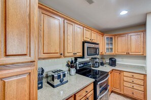 A kitchen with wooden cabinets, a microwave, a toaster, and an oven.