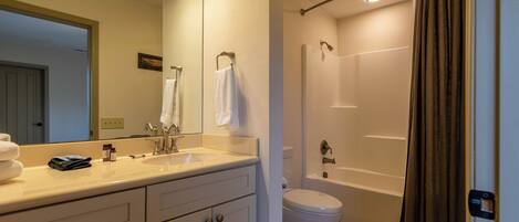 A bathroom with a sink, mirror, toilet, and shower.