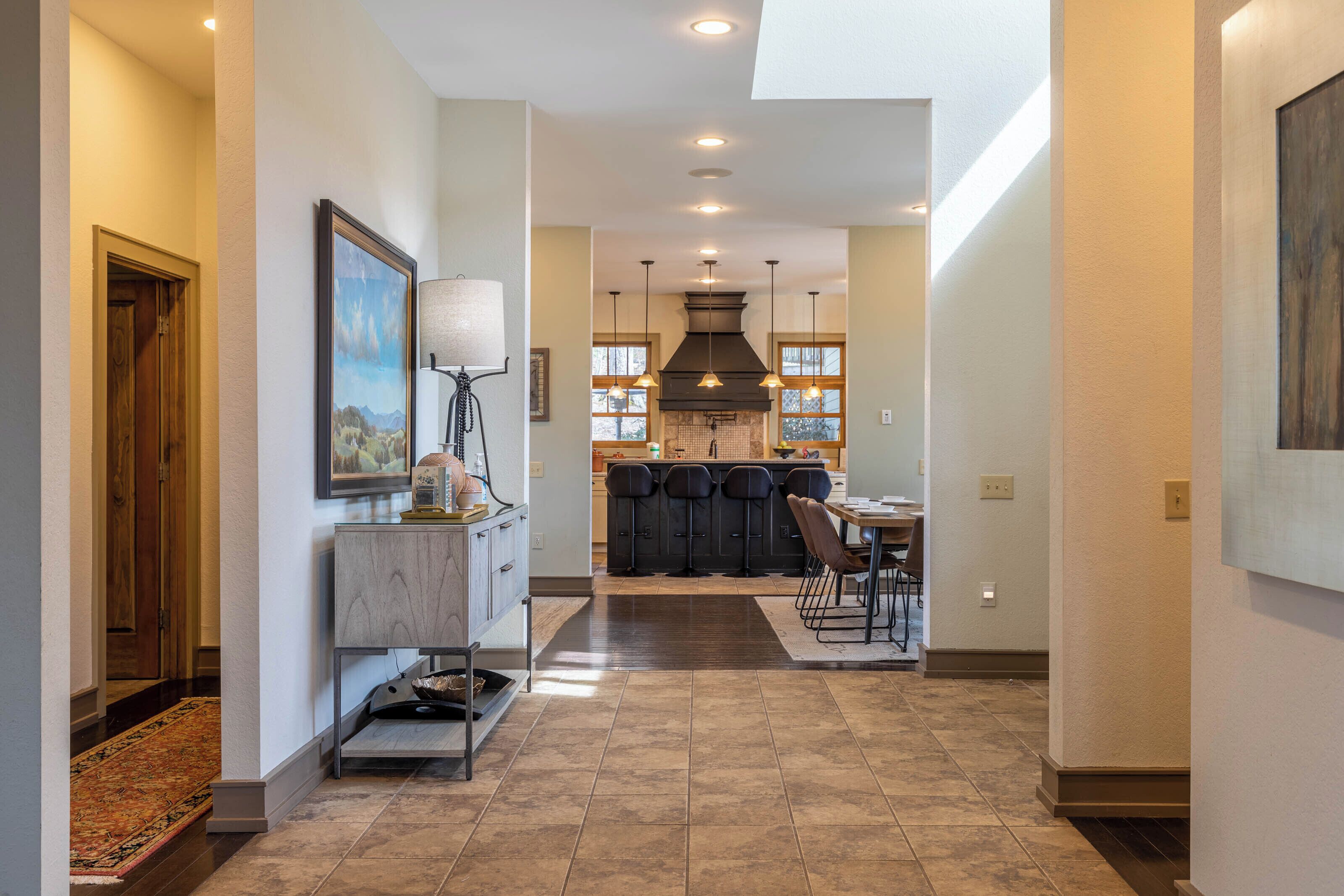 Una cocina moderna con una isla central, iluminación colgante y vistas al área de comedor.