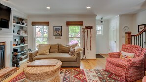 A cozy living room with a beige sofa, a red patterned armchair, a woven ottoman, and a red and beige patterned rug. - The Wander Inn (Blowing Rock)