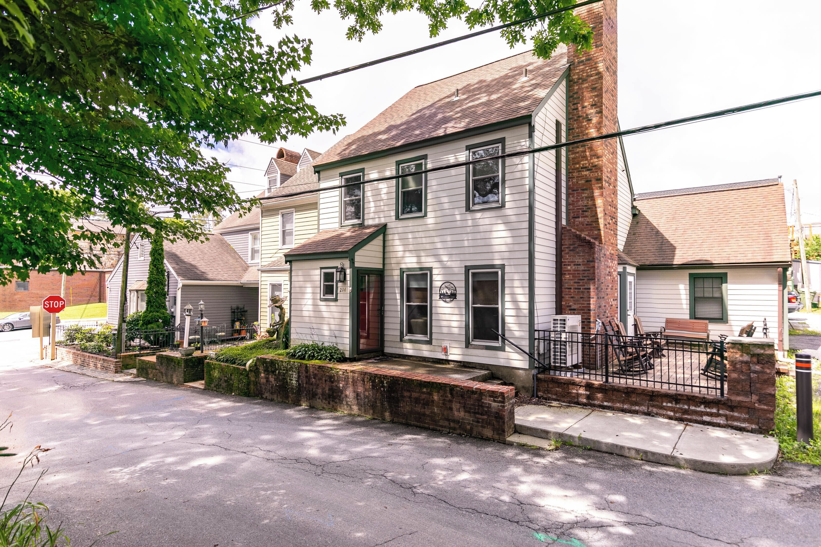 A two-story house with a front porch, a brick chimney, and a mailbox.
