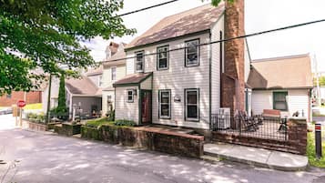 A two-story house with a front porch, a brick chimney, and a mailbox.