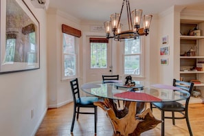 A dining area with a glass table, black chairs, a wooden tree stump centerpiece, and a chandelier. - The Wander Inn (Blowing Rock)