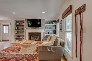 A living room with a fireplace, a television, a sofa, a coffee table, and a patterned rug.