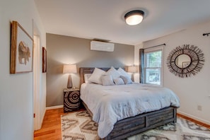 A bedroom with a bed, bedside lamps, a window, a wall-mounted mirror, and a ceiling light fixture. - The Wander Inn (Blowing Rock)