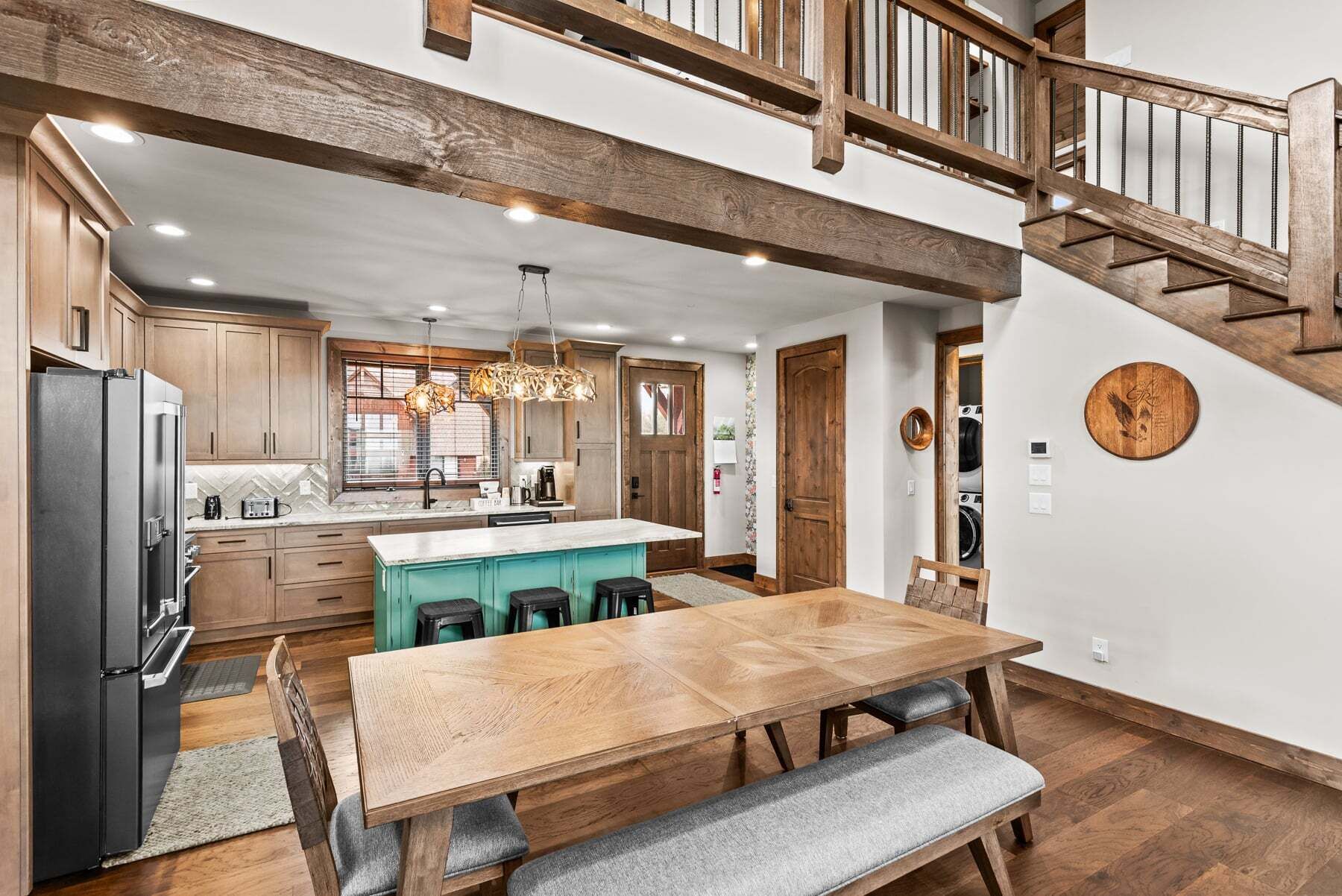 Una cocina con armarios de madera, una isla central y una zona de comedor con mesa y bancos de madera.