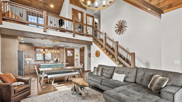 A spacious living area with a large gray sectional sofa, a wooden dining table, and a kitchen in the background. - Eagle Rare Retreat at Eagles Nest (Banner Elk)
