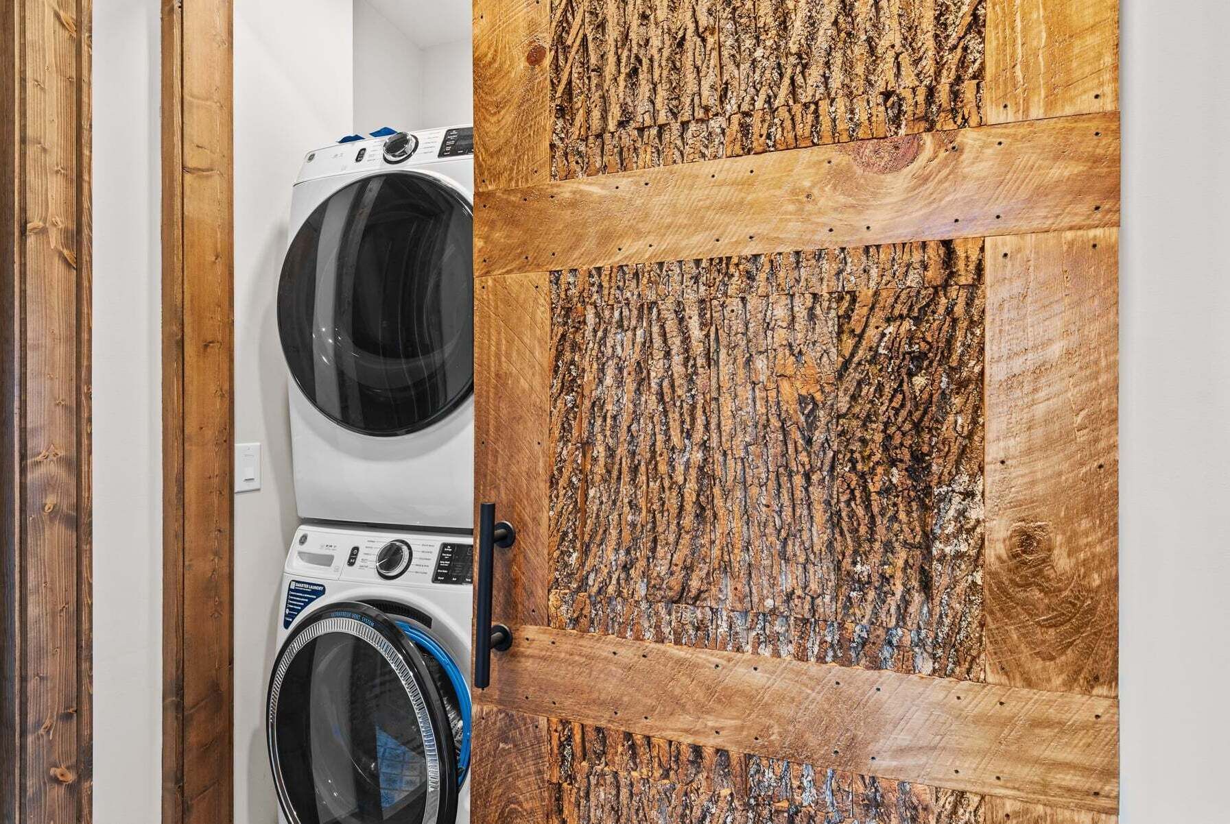 A laundry room with two washing machines and a wooden door.