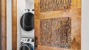 A laundry room with two washing machines and a wooden door. - Eagle Rare Retreat at Eagles Nest (Banner Elk)