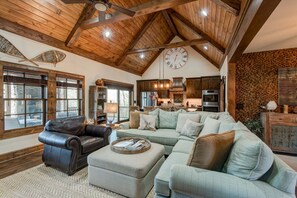 A spacious living room with a large sectional sofa, a leather armchair, and a wooden ceiling with exposed beams. - Bluebird Cottage at Sweetgrass (Blowing Rock)