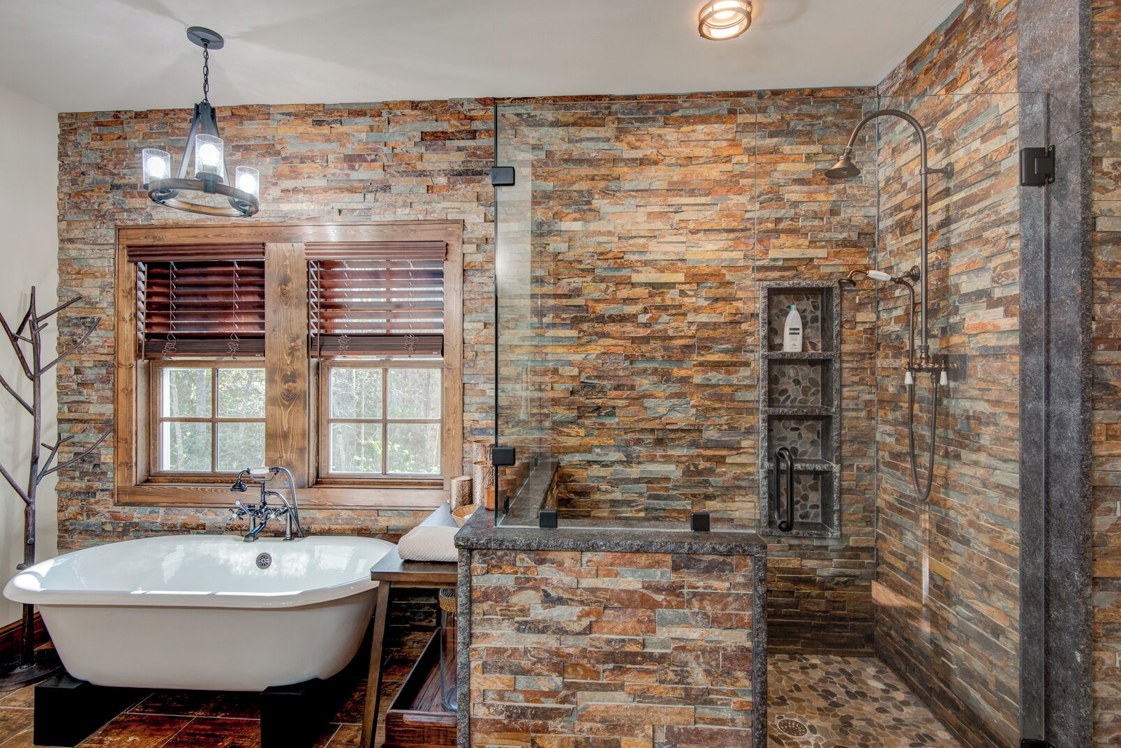 A bathroom with a freestanding bathtub, a shower with a glass enclosure, and a stone wall.