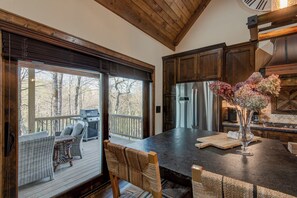 A spacious kitchen with a large island, wooden cabinetry, and a view of the outdoors. - Bluebird Cottage at Sweetgrass (Blowing Rock)