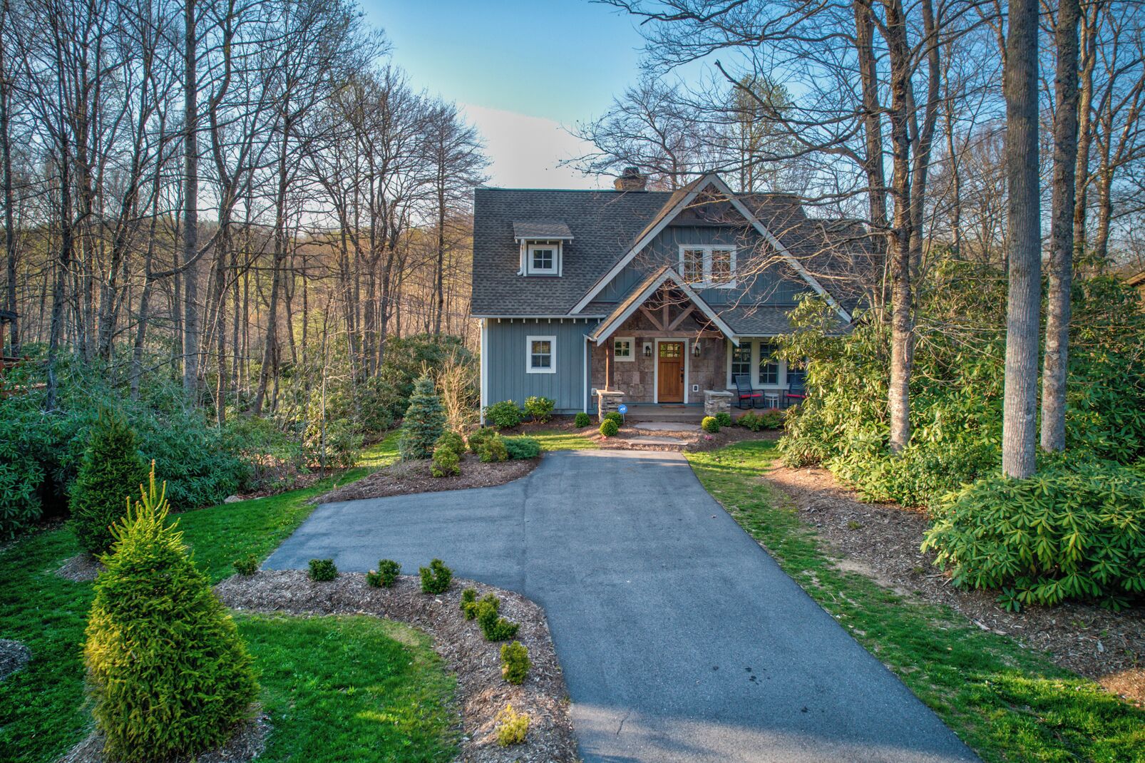 A two-story house with a stone facade, a front porch, and a driveway leading to the entrance.