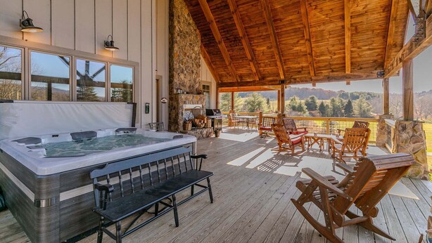 A hot tub in a covered outdoor area with wooden furniture and a stone wall. - Robin Hoods Retreat (Jefferson)