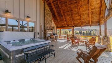 A hot tub in a covered outdoor area with wooden furniture and a stone wall.