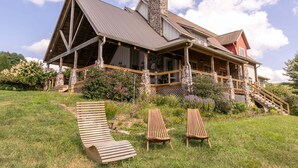 A large house with a stone chimney, a wooden deck, and a stone wall. - Robin Hoods Retreat (Jefferson)