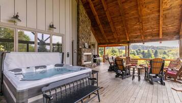 A hot tub on a wooden deck with outdoor seating and a stone wall.