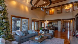 A spacious living area with a large couch, a coffee table, and a Christmas tree. - Horizons Edge (Boone)