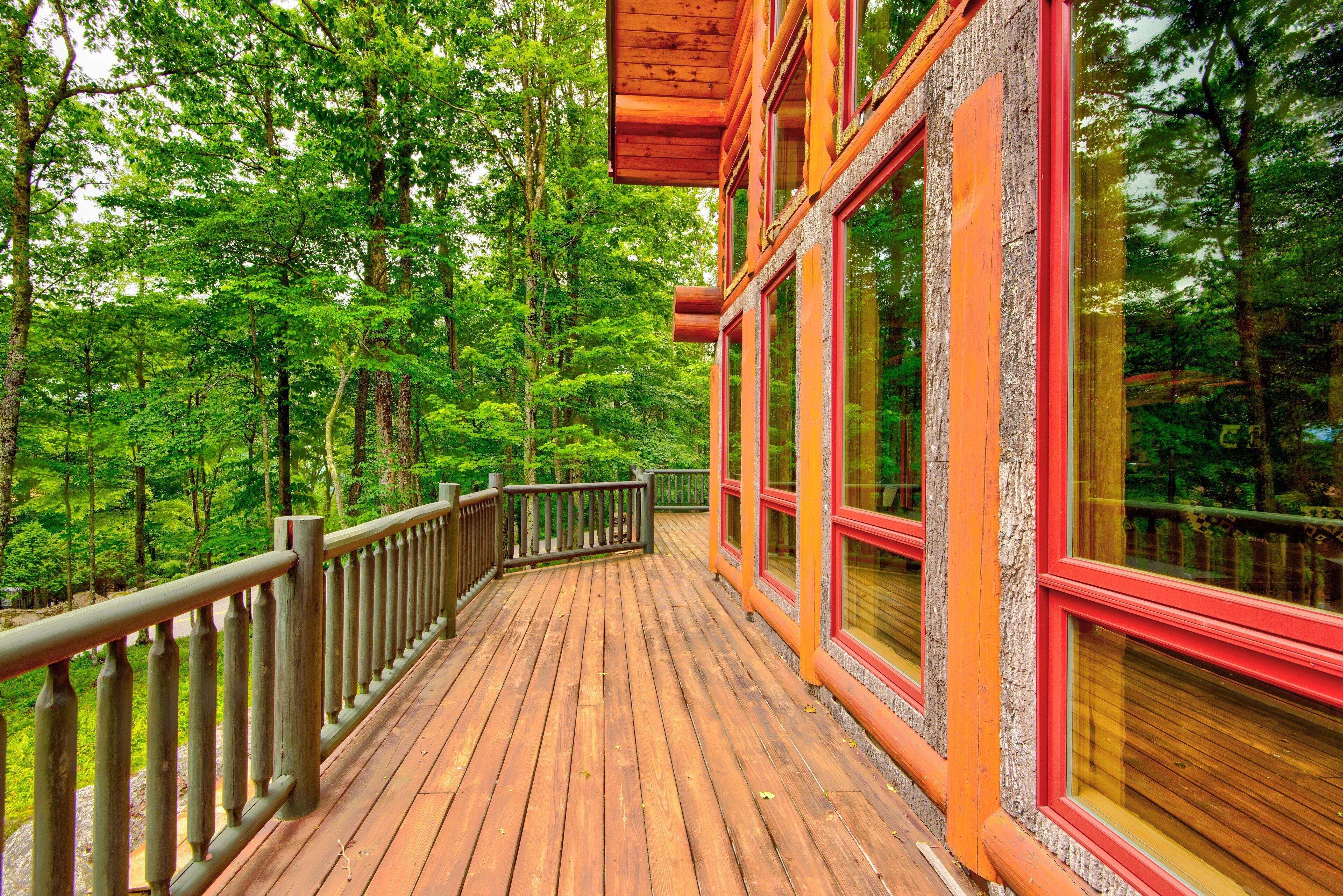 A wooden deck with a railing, surrounded by dense forest.