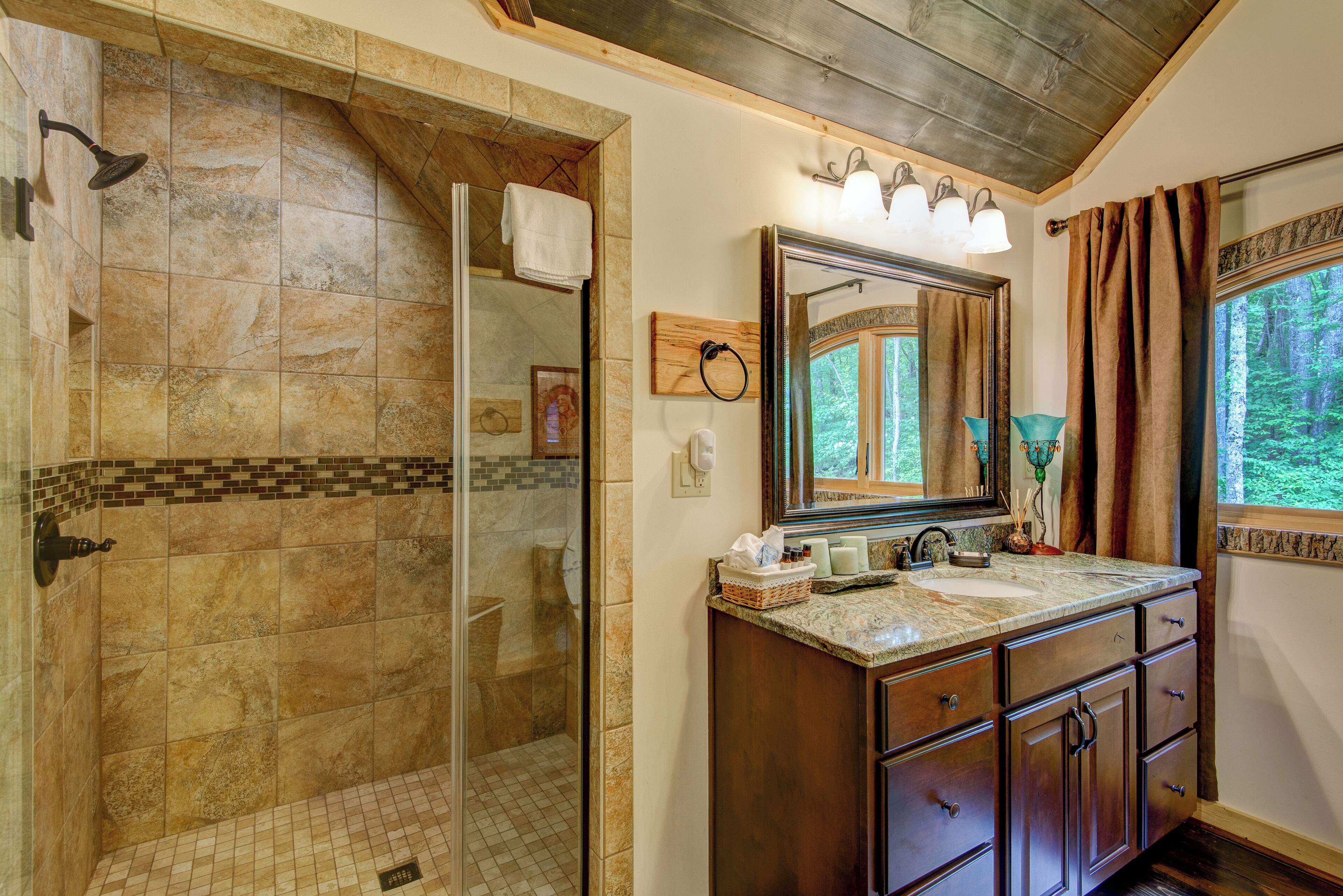 A bathroom with a shower, vanity, and a large mirror.