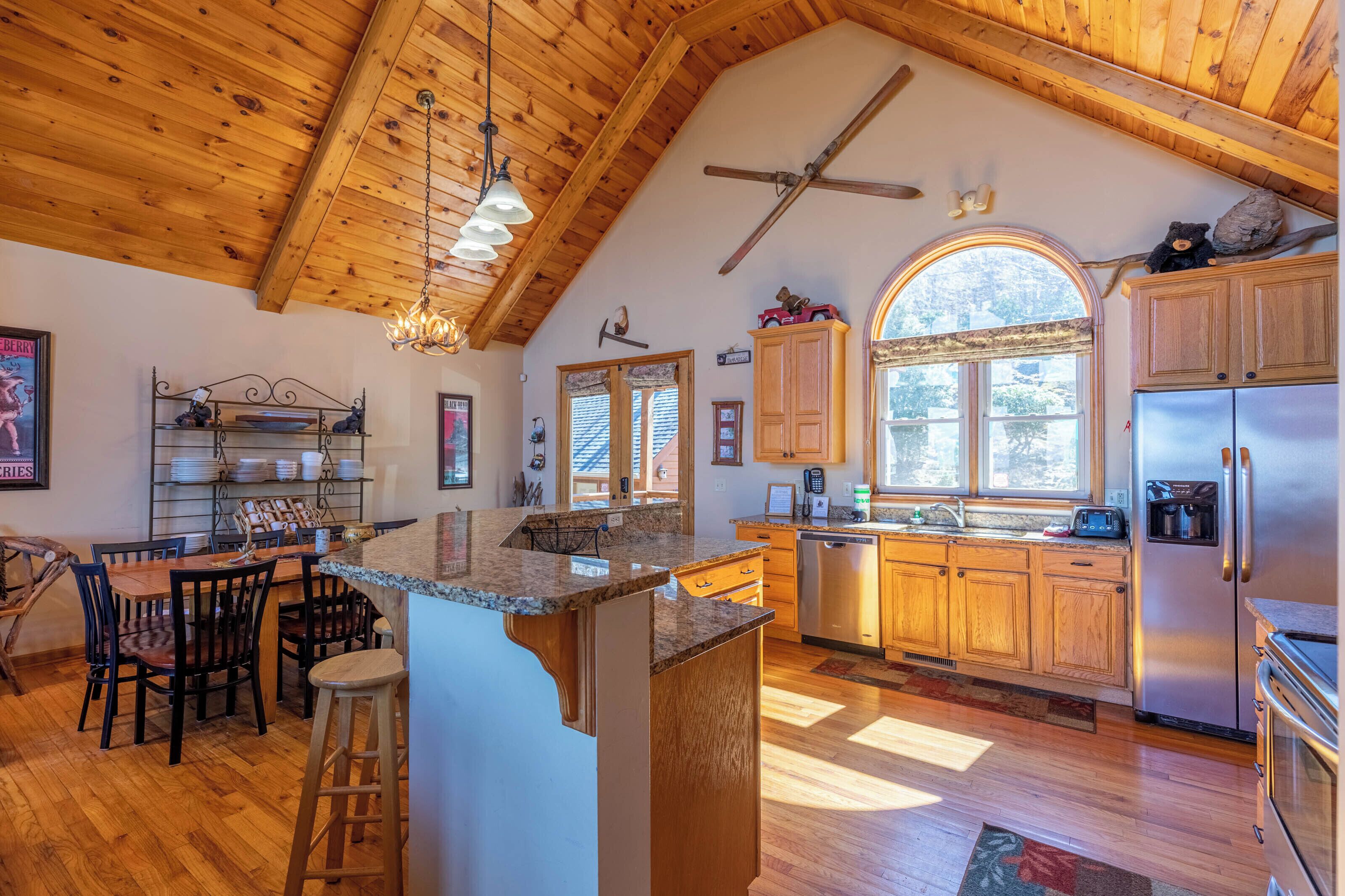 A spacious kitchen with wooden cabinets, a large island, and a dining area with chairs.