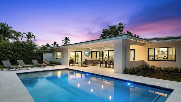 Uma casa moderna com piscina, área de estar externa e um espaço coberto de varanda.