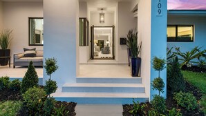 Uma casa moderna com uma entrada bem iluminada, uma escadaria que leva ao interior e o número '2109' na parede.