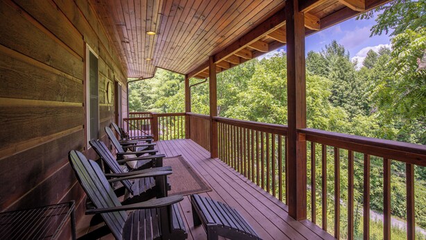 A wooden deck with benches, a wooden railing, and a view of a forested area. - Lazy Bear Inn (Sugar Grove)