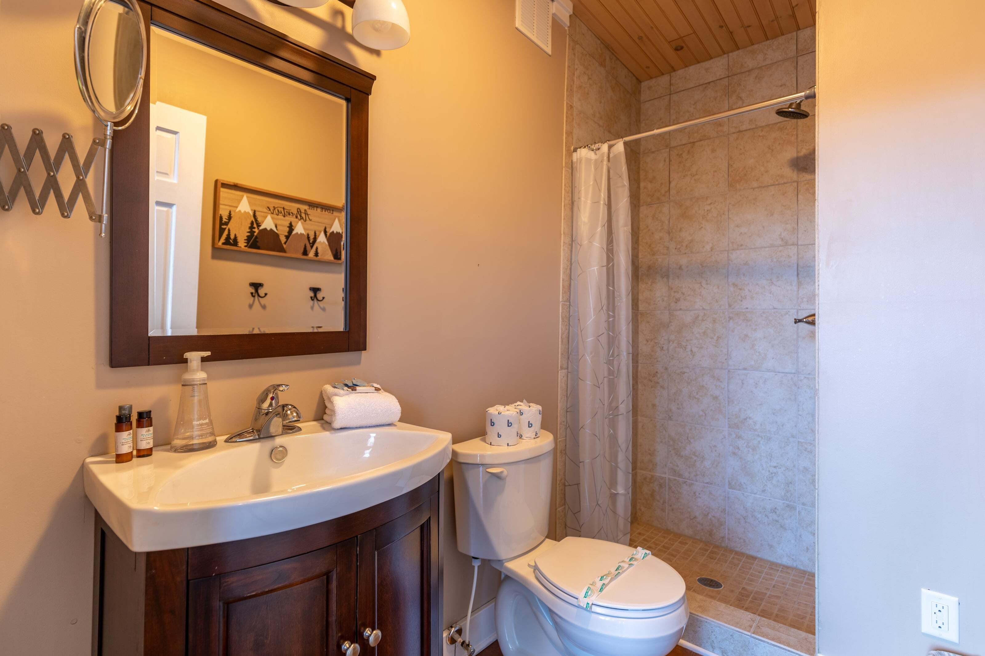 A bathroom with a sink, mirror, toilet, and shower.