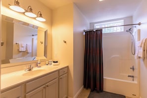 A bathroom with a sink, mirror, vanity, towel rack, shower curtain, and a bathtub. - Watauga River Retreat (Sugar Grove)