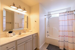 A bathroom with a sink, mirror, vanity, and shower area.