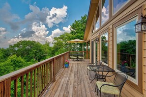 Eine Holzterrasse mit Gartenmöbeln, darunter ein Tisch und Stühle, sowie ein großer Sonnenschirm.