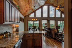 A spacious kitchen with wooden cabinets, a granite countertop, and large windows offering a view of the outdoors. - 1 Beautiful View (Blowing Rock)