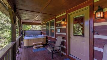 A wooden deck with a hot tub, seating, and a door with a window.
