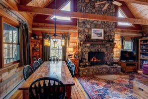 L’intérieur de ce chalet rustique est doté d’une cheminée en pierre, d’une table à manger en bois et d’un coin salon confortable.