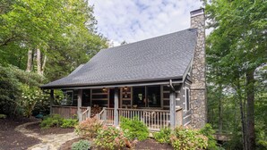 A stone house with a covered porch, surrounded by trees and a stone pathway. - Scarborough Fair (Banner Elk)