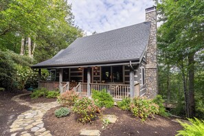 A stone house with a covered porch, surrounded by trees and a stone pathway. - Scarborough Fair (Banner Elk)