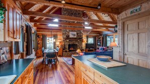 A log cabin interior with a stone fireplace, wooden dining table, and a cozy seating area. - Scarborough Fair (Banner Elk)