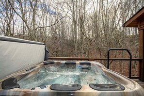 A hot tub with a wooden deck and a metal railing, surrounded by trees. - Overlook Nook at Eagles Nest (Elk Park)