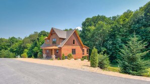 A two-story wooden house with a front porch, surrounded by dense forest. - Overlook Nook at Eagles Nest (Elk Park)