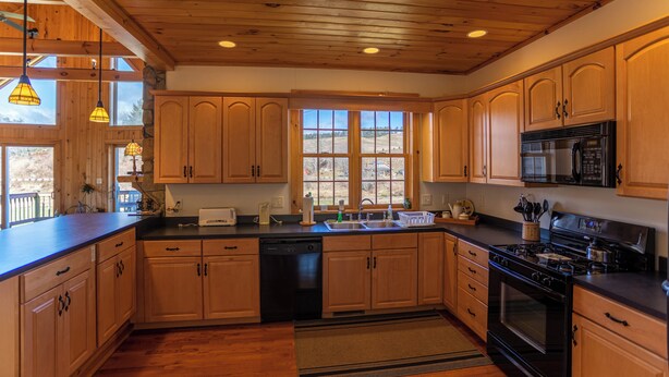 A kitchen with wooden cabinets, a dishwasher, a stove, and a microwave. - River House at Meadow Landing (Fleetwood)