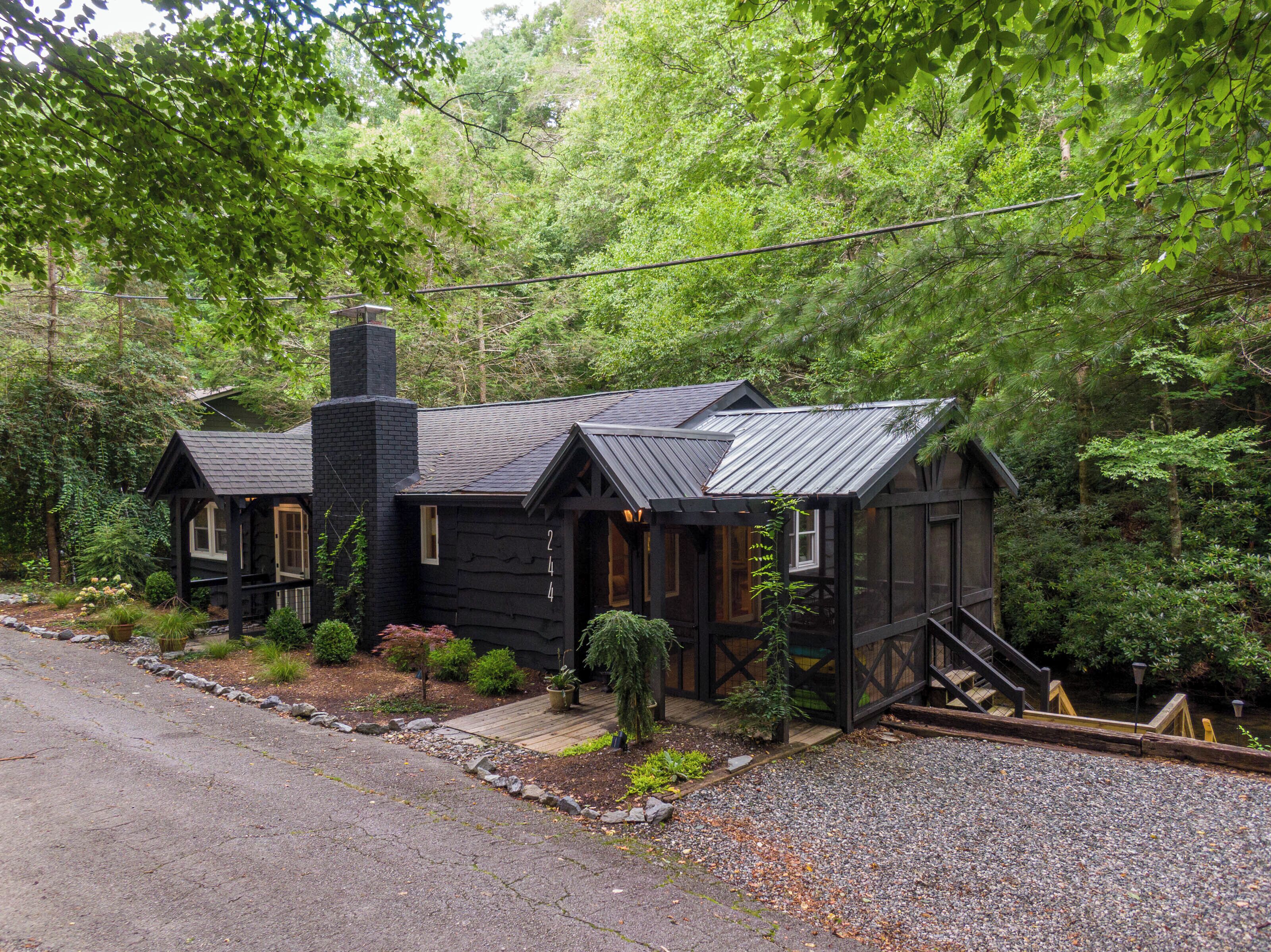 Une cabane avec une cheminée, un revêtement extérieur en bois et un petit porche.