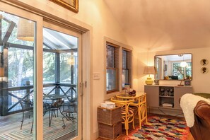 A cozy room with a dining table, chairs, a wicker basket, a sofa, a mirror, and a window with blinds. - Anglers Cottage (Blowing Rock)