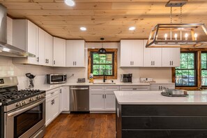 A modern kitchen with white cabinets, stainless steel appliances, and a large island.