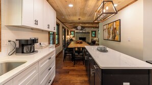 A modern kitchen with white cabinets, a wooden ceiling, and a central island with seating. - Moosey Creek Lodge (Banner Elk)