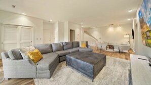 A modern living room with a sectional sofa, ottoman, and a staircase leading to another level. - Banner Elk Valley Overlook (Banner Elk)